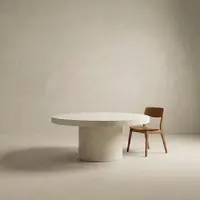 Studio render of the Athina round bone-white concrete dining table with a single timber chair on a soft neutral backdrop