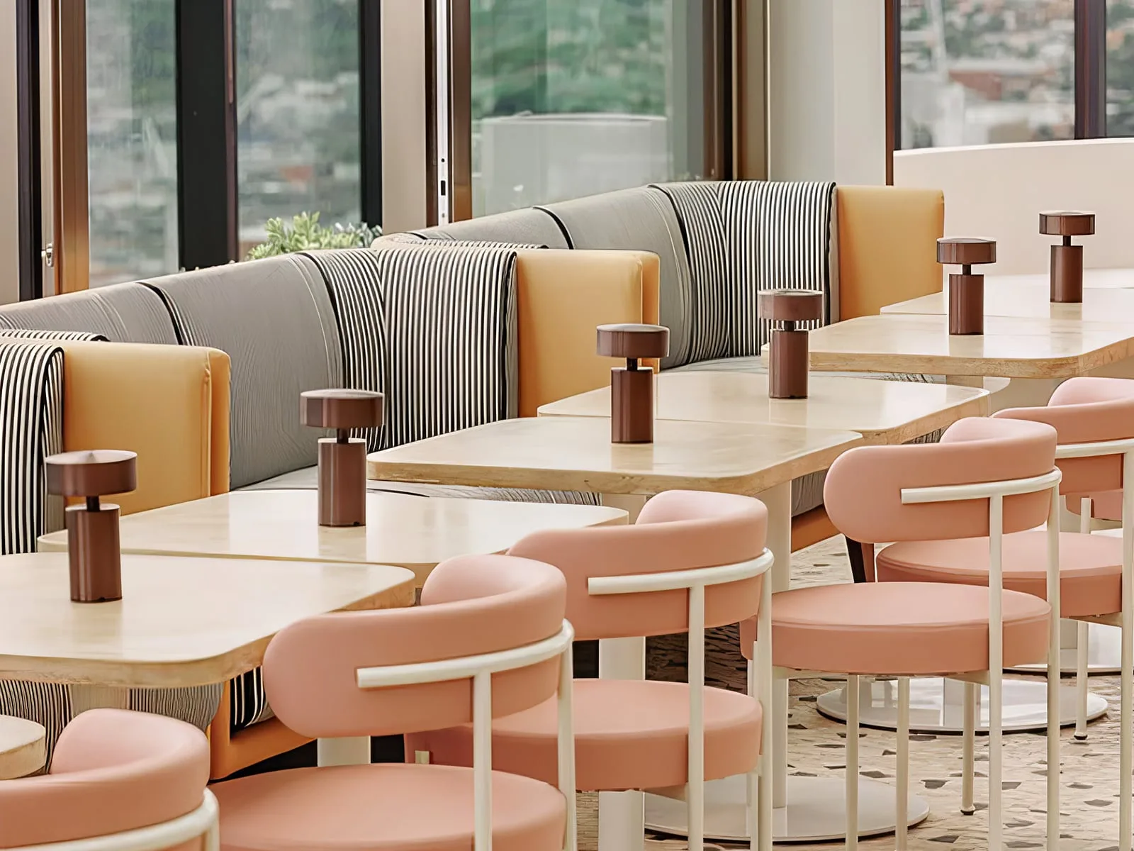 Concrete cafe tables paired with peach round chairs and striped banquette seating at The Beverly Rooftop in South Yarra