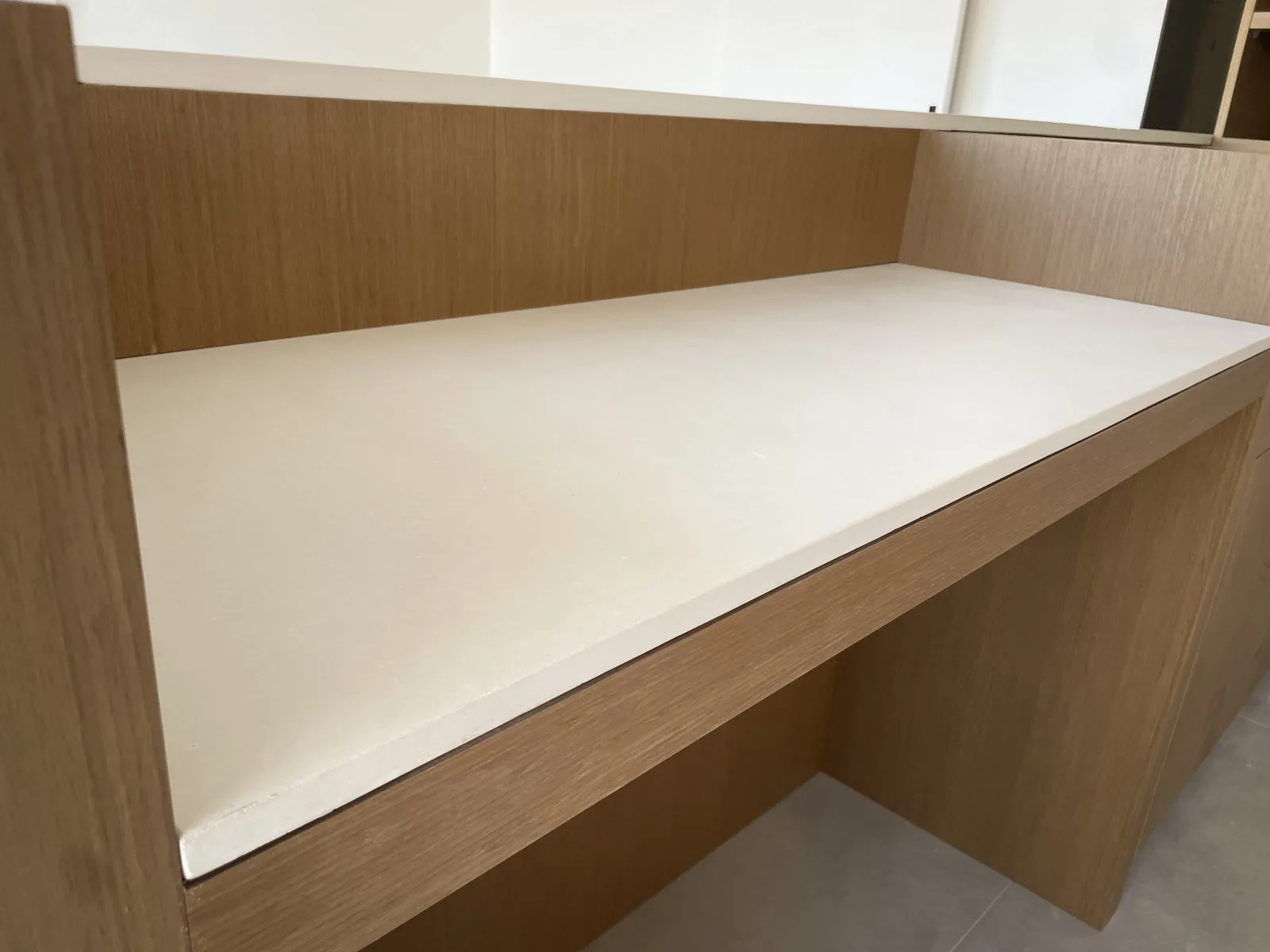 Detail of the bone white concrete benchtop edge against timber drawer fronts in the Elsternwick custom-built kitchen