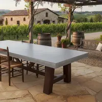 Farmhouse concrete dining table outdoors under a wisteria-covered pergola with Tuscan vineyard view