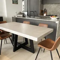IronCross concrete dining table in a modern kitchen with tan leather chairs and grey marble island