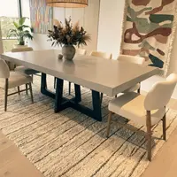 IronCross concrete dining table with boucle chairs, dried-flower vase, and tapestry wall hanging
