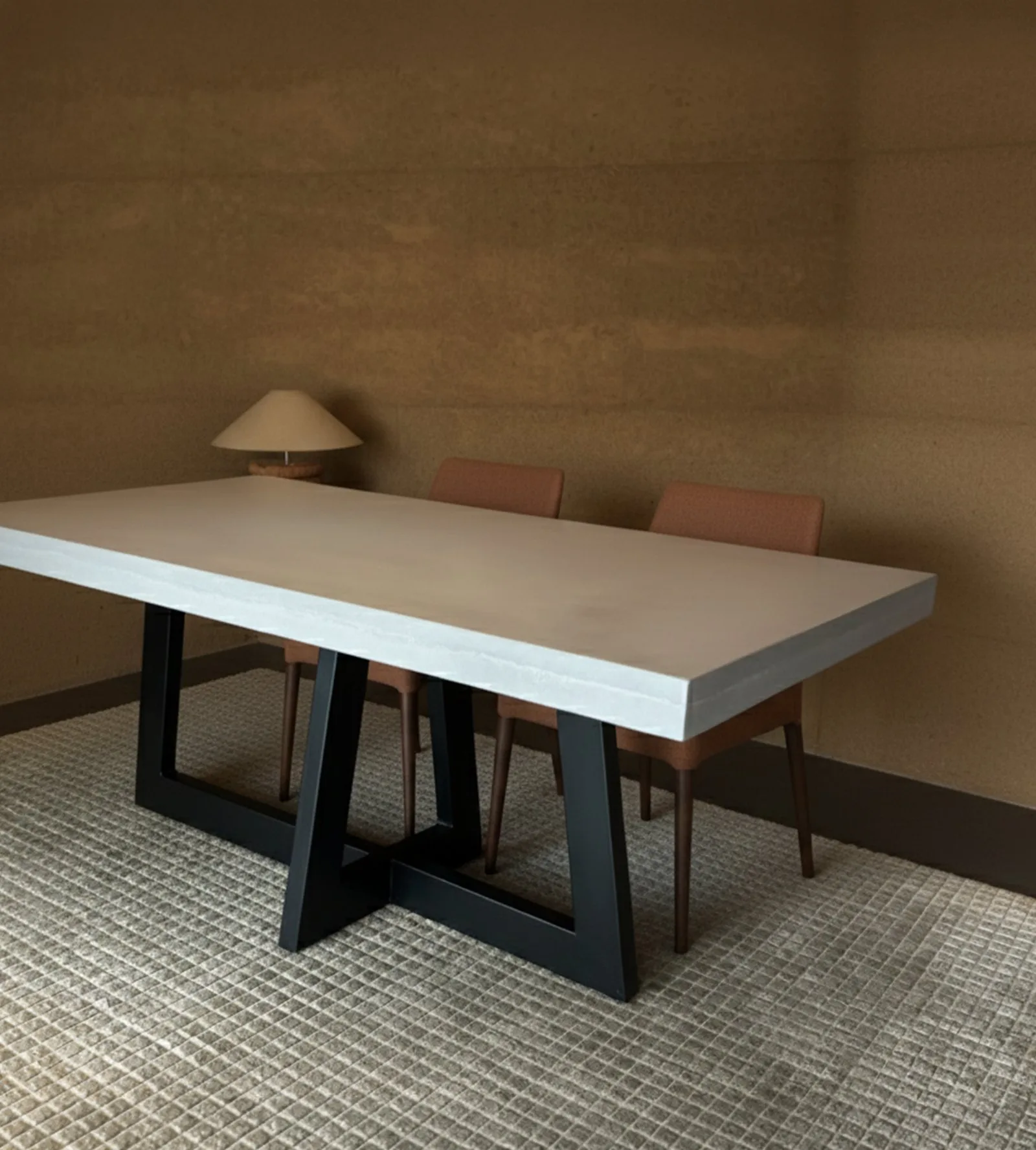 IronCross concrete dining table with terracotta chairs and warm ochre walls