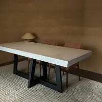 IronCross concrete dining table with terracotta chairs and warm ochre walls