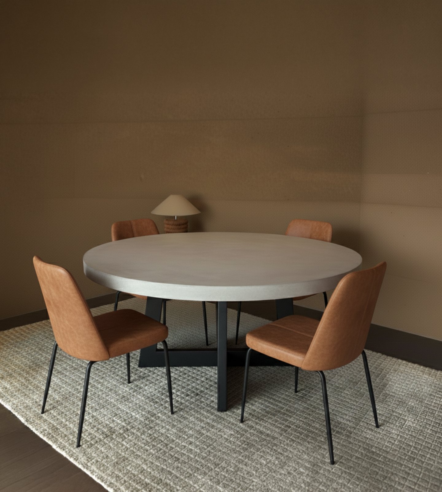 Round IronCross concrete dining table in a warm interior with four tan leather chairs and a paper-shade table lamp