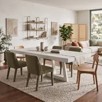 IronCross concrete dining table in an open-plan living room with olive-green velvet dining chairs, oak chair, brass shelving and linen sofa