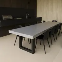 IronStone concrete dining table in an outdoor kitchen with BBQ and black chairs