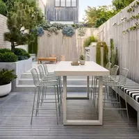 IronStone concrete bar table in an outdoor courtyard with bar stools, built-in bench seat and lush green planters against a white wall