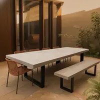 IronStone concrete dining table and bench seat in light grey on a sandstone patio with rope chairs and lush courtyard planting