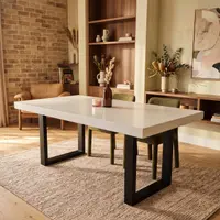White IronStone concrete dining table in a brick-and-walnut living-dining room with olive velvet chairs