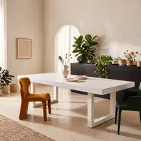 White IronStone concrete dining table in a sunlit plaster interior with arched window, fiddle-leaf fig and mustard wing chair