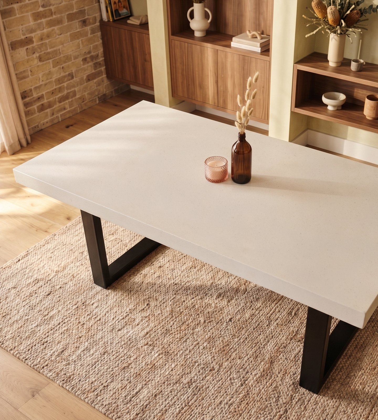Overhead view of the white IronStone concrete dining table with black steel legs on jute rug, walnut shelving and brick wall