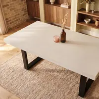Overhead view of the white IronStone concrete dining table with black steel legs on jute rug, walnut shelving and brick wall