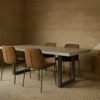 IronStone concrete dining table with rust-coloured upholstered chairs in a rammed-earth dining room