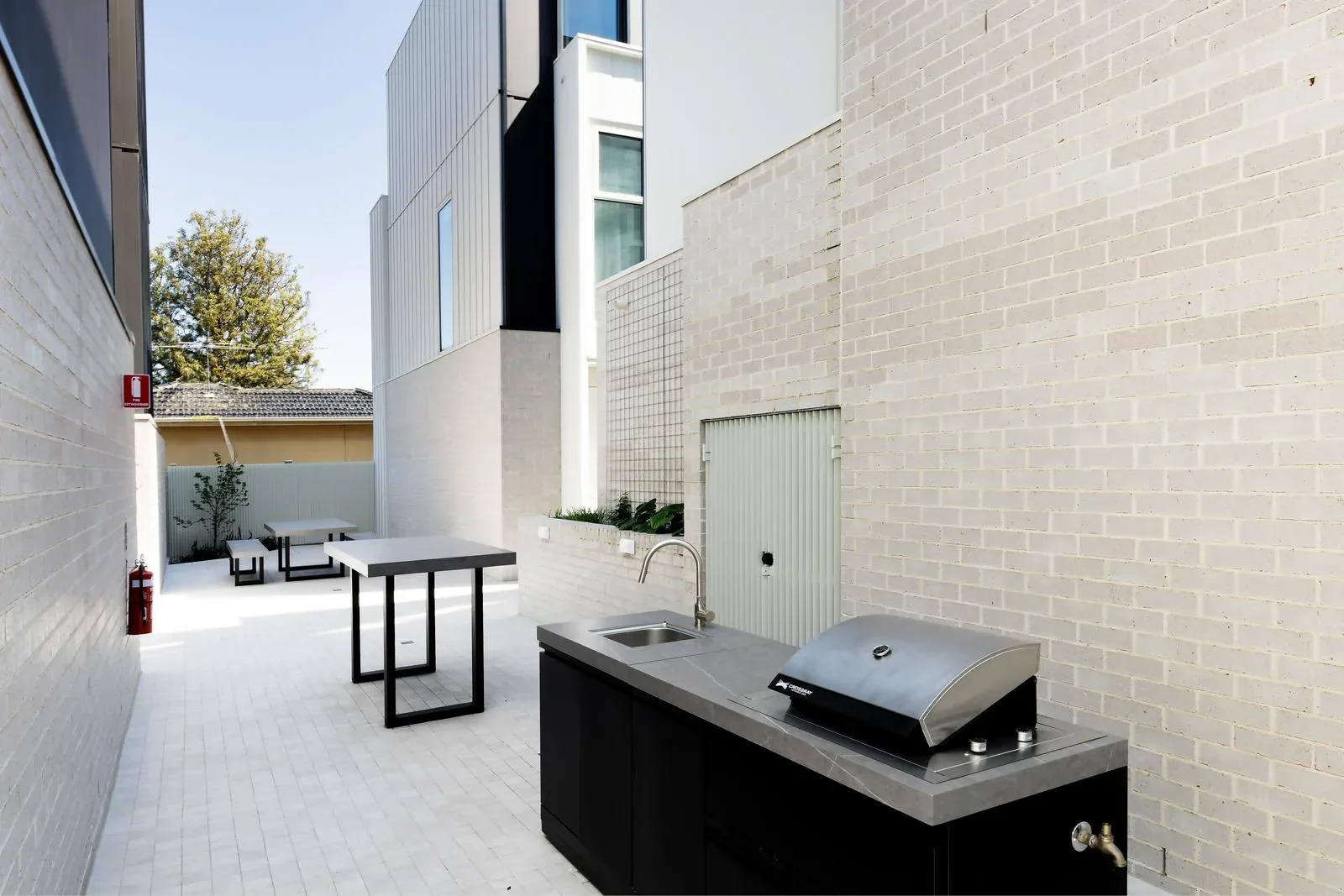 Brick-walled garden pathway at the 93 Earl Street Kew development, where SnapCo bench seats run between the communal entertaining zones and the residential entries