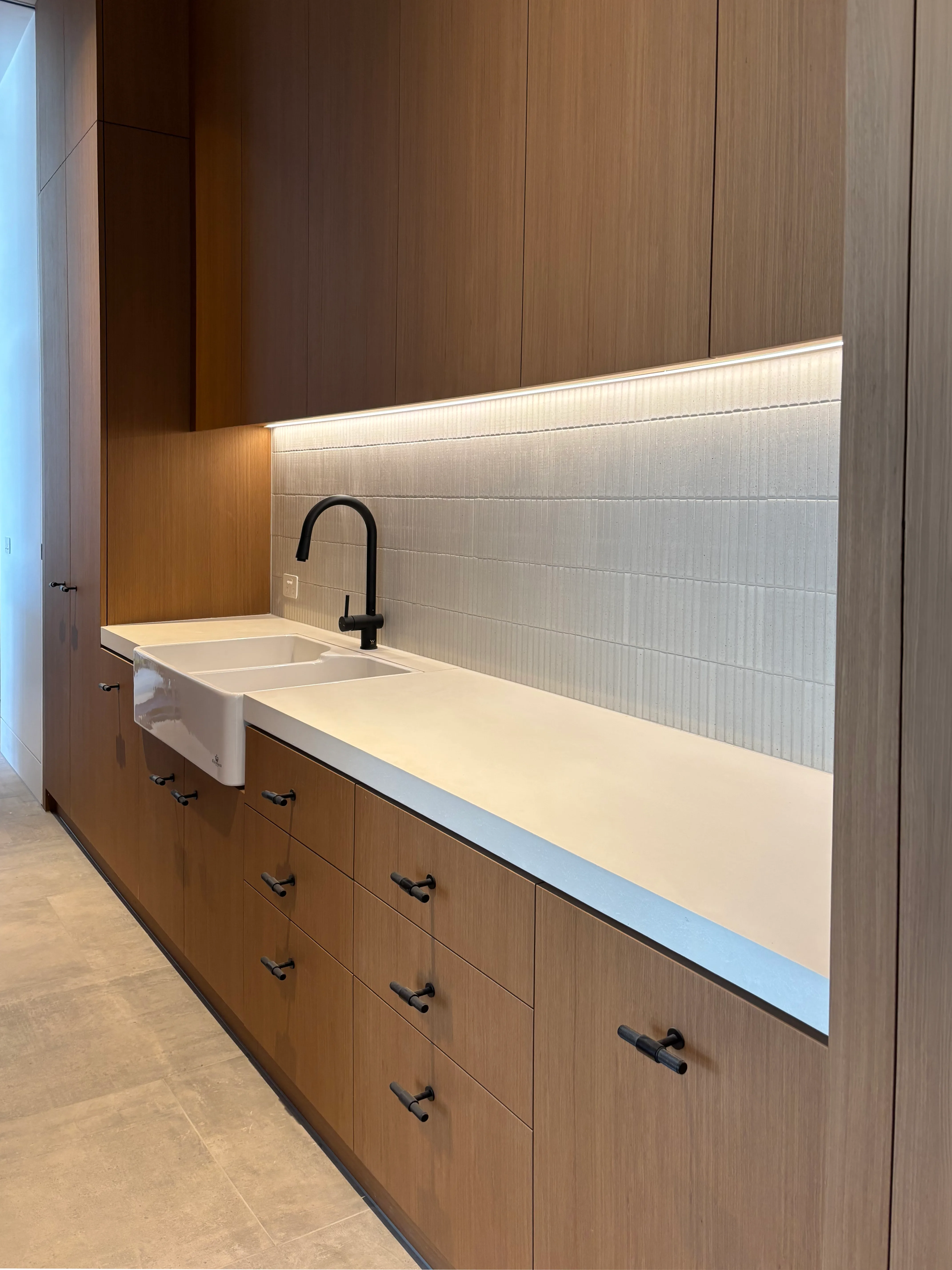Bone-white concrete kitchen benchtop with stainless butler sink and ribbed tile splashback, hand-cast by SnapCo
