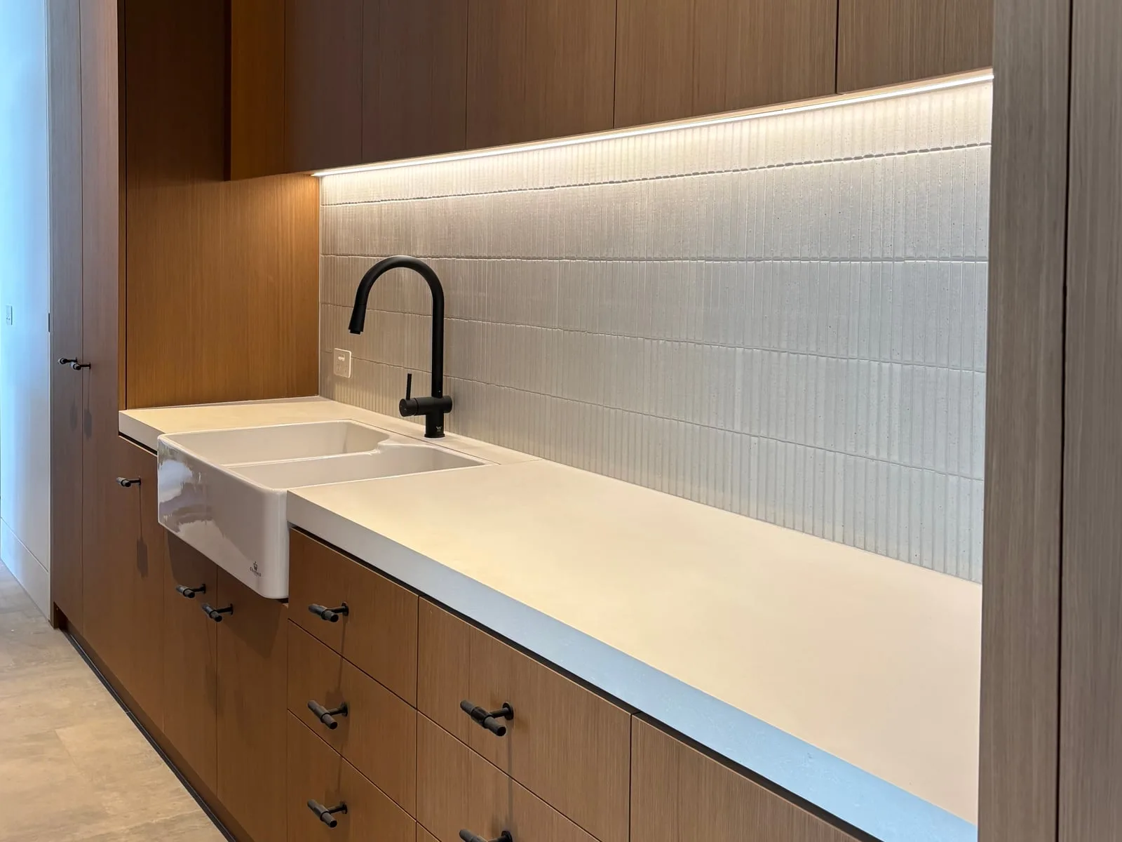 Bone-white concrete kitchen benchtop with stainless butler sink and ribbed tile splashback, hand-cast by SnapCo