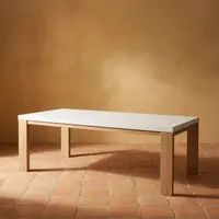 Laconian concrete dining table with white top and oak legs on terracotta tile against a warm ochre plaster wall
