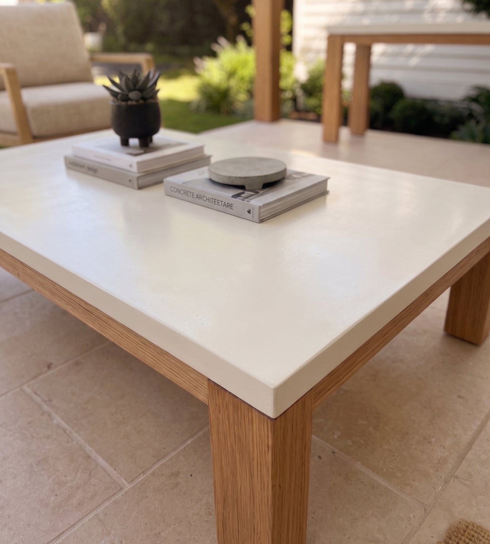 Laconian concrete coffee table close-up with succulent, architecture books, and concrete object on stone patio