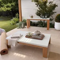 Laconian white concrete coffee table on a paved garden patio with linen throw, lanterns, and matching console table