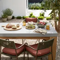 Laconian concrete dining table styled with bread, fruit, and brass tableware in a Mediterranean garden