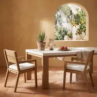 Laconian concrete dining table with bone-white top in a Mediterranean room with arched window onto olive and citrus trees