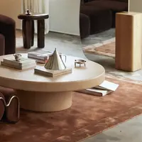 Milano round oyster concrete coffee table close-up with cone sculpture, books and brown velvet seating