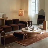 Milano round oyster concrete coffee table in a warm room with brown velvet sofas, rattan lamp and rust-tone rug