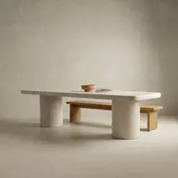 Milano rectangular white concrete dining table on twin cylindrical concrete pedestals, paired with a solid oak bench tucked alongside, terracotta bowl and dried grasses on top, studio render on a soft neutral backdrop