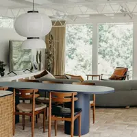 Navy Palermo oval concrete dining table with timber chairs and paper lanterns in a sunlit living space