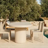 Palermo oval concrete dining table by an infinity pool under an old olive tree, paired with parsons chairs and a rattan daybed