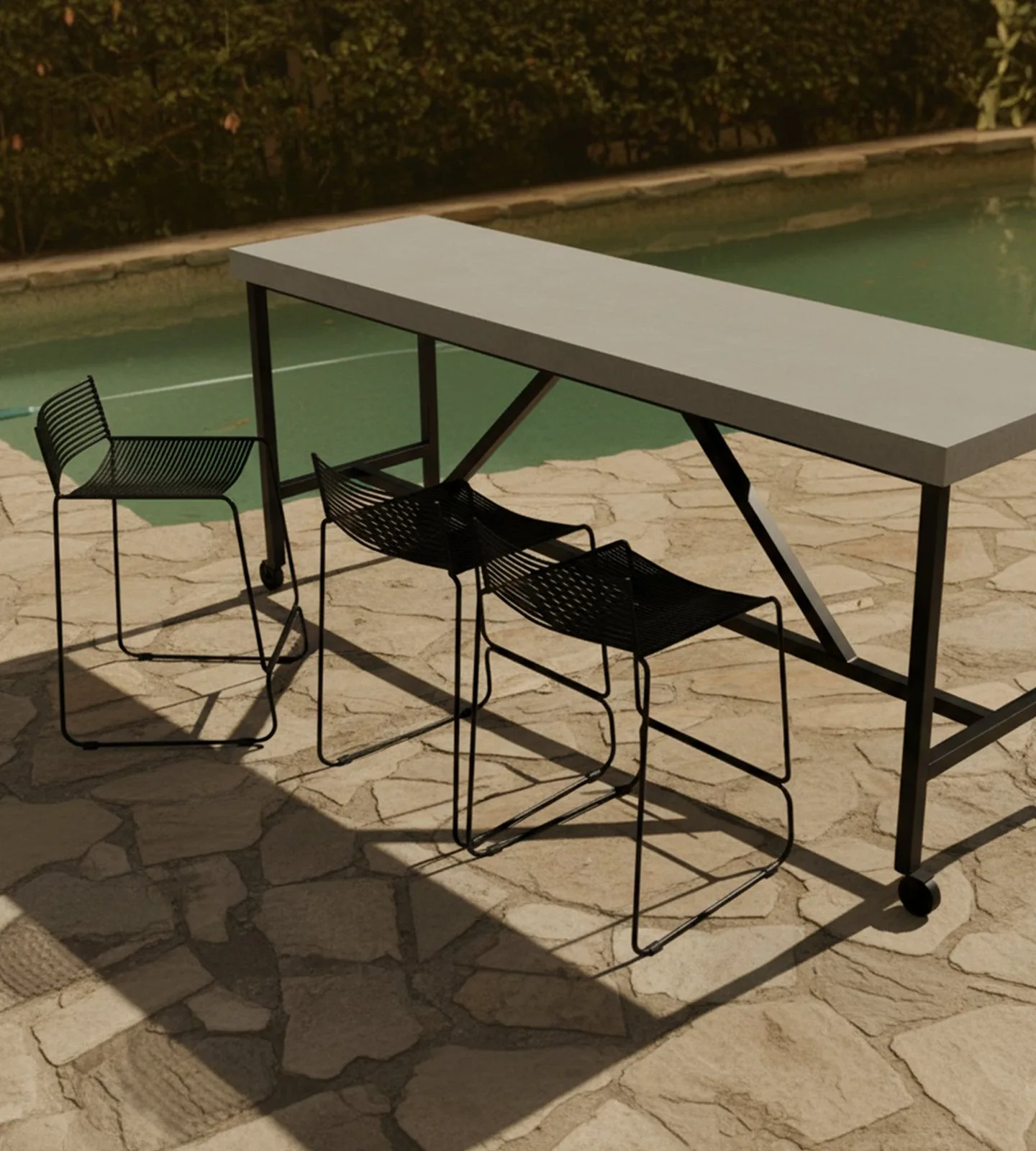 Santino concrete bar table by a pool with black wire bar stools on a flagstone terrace