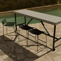 Santino concrete bar table by a pool with black wire bar stools on a flagstone terrace