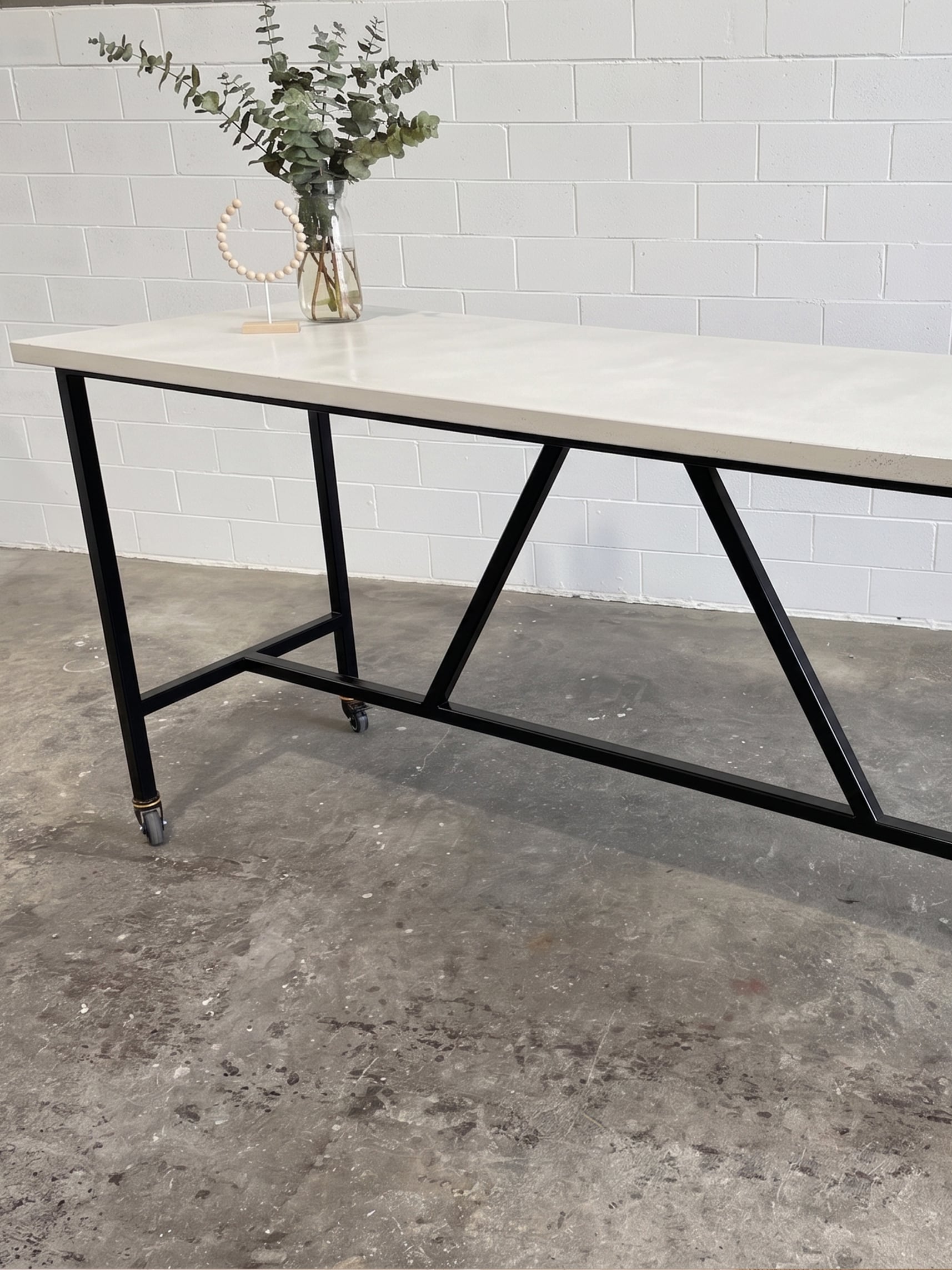 SnapCo Santino concrete bar table with bone-white top and steel base, in situ side angle