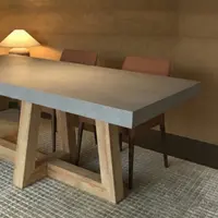TimberCross concrete dining table in a warm dim-lit room with terracotta dining chairs and lamp
