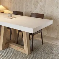 Corner detail of the TimberCross white concrete dining table with walnut chairs, a stone coaster and ceramic vessel on a travertine-walled set