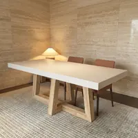 TimberCross white concrete dining table in a travertine-walled dining room with a warm dome lamp and rust-coloured upholstered chairs