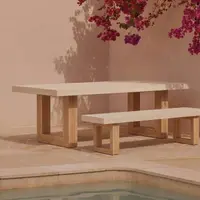 TimberStone concrete dining table and bench seat in Bone White beside a pool with bougainvillea overhead and pink plaster wall