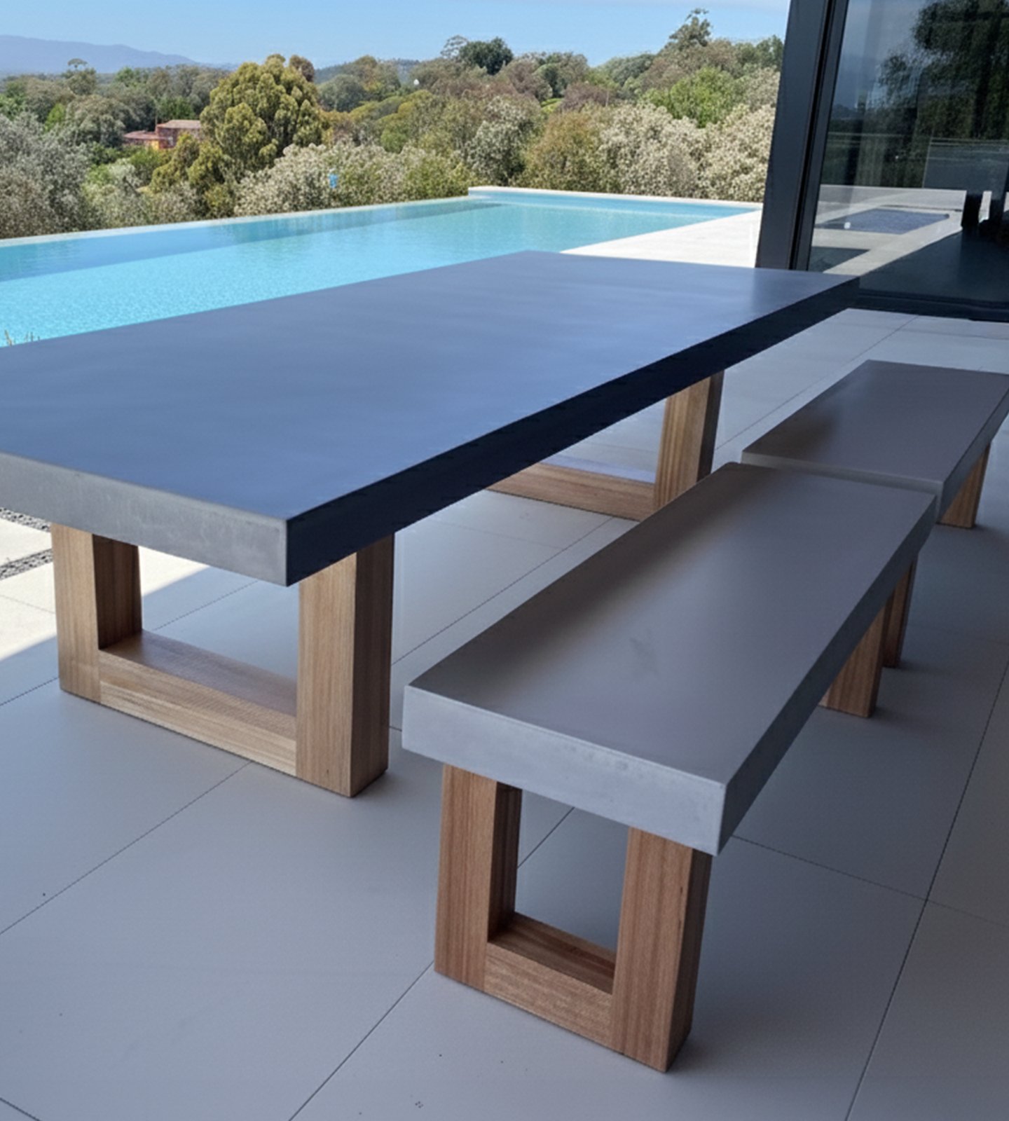 TimberStone concrete dining table and bench seat on a poolside terrace overlooking an infinity pool and bushland