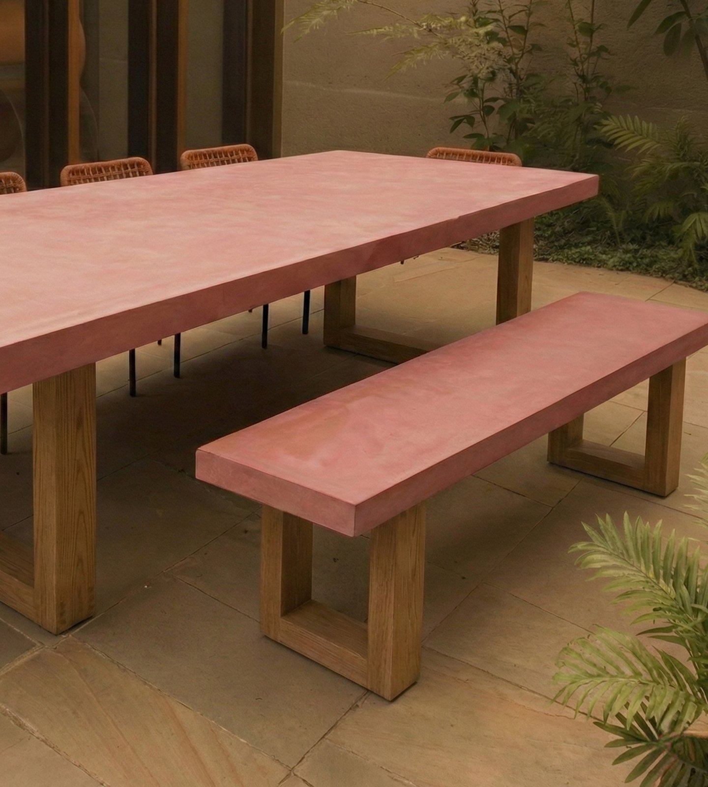 TimberStone concrete dining table and bench seat in terracotta pigment on a sandstone courtyard at dusk with rope chairs