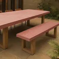 TimberStone concrete dining table and bench seat in terracotta pigment on a sandstone courtyard at dusk with rope chairs